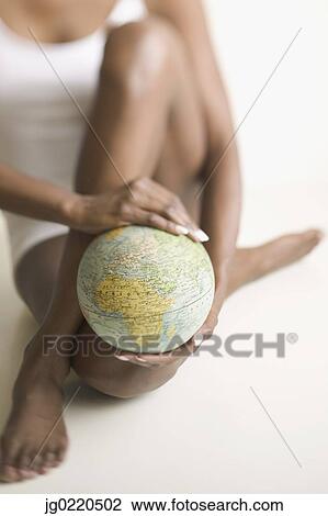 Stock Image - Portrait of a young woman holding a globe. Fotosearch