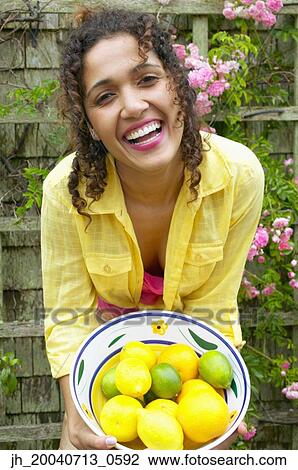 Portrait of a young woman holding a basket of fruit smiling View Large Photo Image Stock Image - Portrait of a young woman holding a basket of fruit smiling. Fotosearch