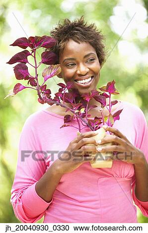 Portrait of a young woman holding a plant smiling View Large Photo Image Stock Image - Portrait of a young woman holding a plant smiling. Fotosearch