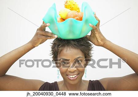 Portrait of a young woman holding a fruit bowl over her head View Large Photo Image Stock Photo - Portrait of a young woman holding a fruit bowl over her head. Fotosearch