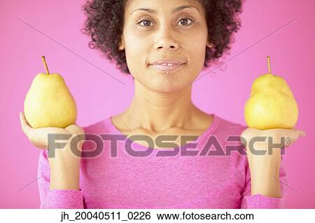 Portrait of a young woman holding a pear in each hand View Large Photo Image Stock Photograph - Portrait of a young woman holding a pear in each hand. Fotosearch
