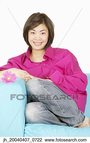 Portrait of a young woman sitting on a couch View Large Photo Image Stock Image - Portrait of a young woman sitting on a couch. Fotosearch