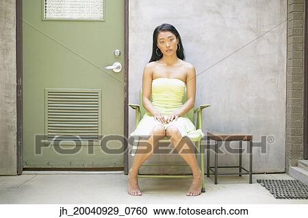 Portrait of a young woman sitting on a chair View Large Photo Image Stock Image - Portrait of a young woman sitting on a chair. Fotosearch