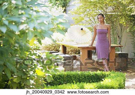 Portrait of a young woman standing against a table View Large Photo Image Stock Image - Portrait of a young woman standing against a table. Fotosearch