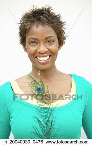 Portrait of a young woman standing holding a peacock feather smiling View Large Photo Image Stock Photograph - Portrait of a young woman standing holding a peacock feather smiling. Fotosearch