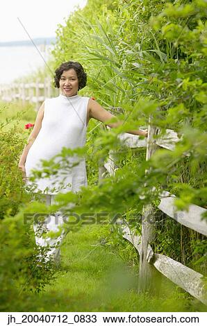 Portrait of mid adult woman leaning against a railing View Large Photo Image Stock Image - Portrait of mid adult woman leaning against a railing. Fotosearch