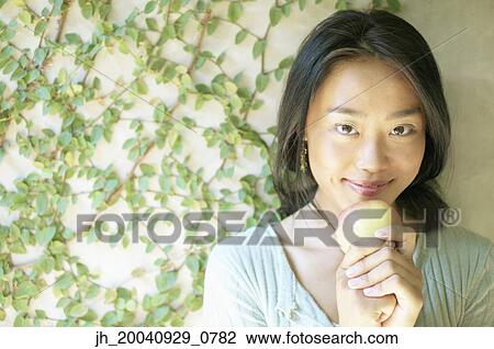 Portrait of young woman holding an apple smiling View Large Photo Image Stock Image - Portrait of young woman holding an apple smiling. Fotosearch