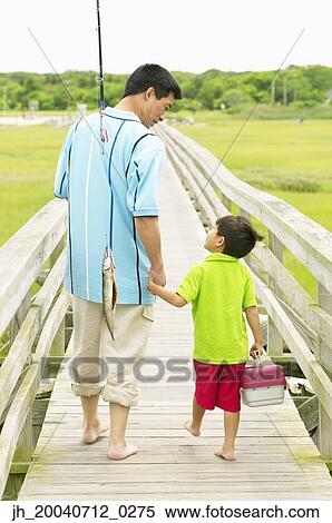 Rear view of a father and his son walking on a pier holding fishing gear View Large Photo Image Stock Photography - Rear view of a father and his son walking on a pier holding fishing gear. Fotosearch
