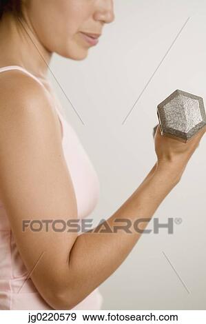 Stock Photo - Side profile of a woman exercising with dumbbells. Fotosearch