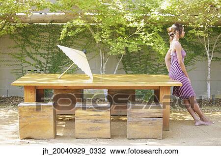 Side profile of a young woman leaning against a table View Large Photo Image Stock Image - Side profile of a young woman leaning against a table. Fotosearch