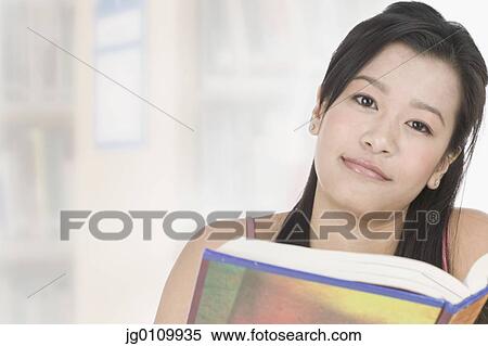 Stock Photography - Teenage girl holding a book looking at camera. Fotosearch