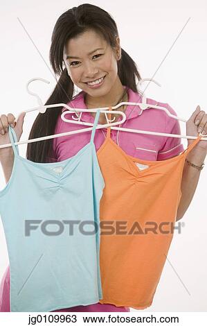 Stock Image - Teenage girl holding two tops in front of her. Fotosearch