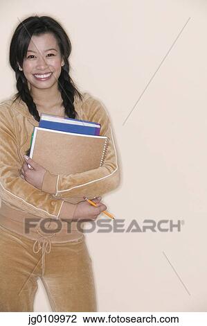 Teenage girl standing holding books smiling View Large Photo Image Stock Image - Teenage girl standing holding books smiling. Fotosearch