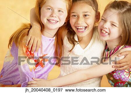 Three young girls holding each other smiling View Large Photo Image Stock Photo - Three young girls holding each other smiling. Fotosearch