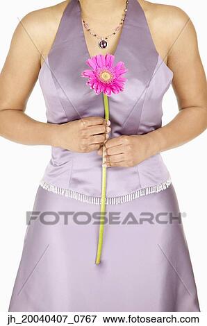 Torso of a young woman holding a flower View Large Photo Image Stock Photo - Torso of a young woman holding a flower. Fotosearch