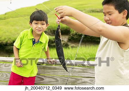 Two young boys holding a fish View Large Photo Image Stock Photo - Two young boys holding a fish. Fotosearch