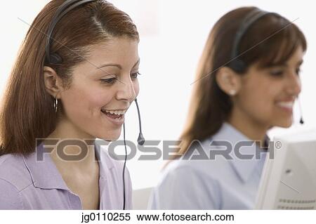 Two young women talking on phone headsets smiling View Large Photo Image Stock Photography - Two young women talking on phone headsets smiling. Fotosearch