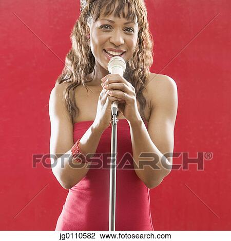 Woman holding a microphone stand singing View Large Photo Image Stock Image - Woman holding a microphone stand singing. Fotosearch
