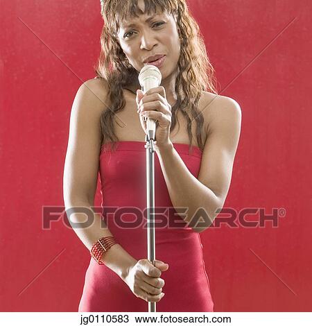 Stock Image - Woman holding a microphone stand singing. Fotosearch