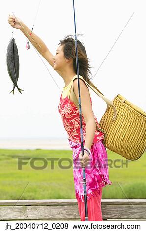 Woman standing holding fish View Large Photo Image Stock Photo - Woman standing holding fish. Fotosearch