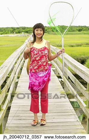 Woman standing on a pier holding a fishing net View Large Photo Image Stock Photo - Woman standing on a pier holding a fishing net. Fotosearch