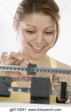 Stock Image - Woman standing on a weighing scale. Fotosearch