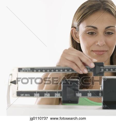 Stock Photo - Woman standing on a weighing scale. Fotosearch