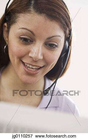 Stock Photo - Woman talking on a headset smiling. Fotosearch
