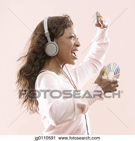 Woman wearing headphones holding a compact disc dancing View Large Photo Image Stock Image - Woman wearing headphones holding a compact disc dancing. Fotosearch