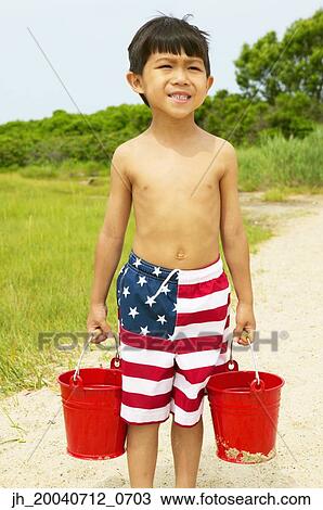 Young boy carrying two buckets at the beach View Large Photo Image Stock Image - Young boy carrying two buckets at the beach. Fotosearch