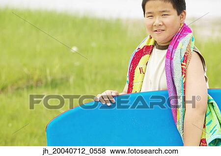 Young boy holding a boogie board smiling View Large Photo Image Stock Photo - Young boy holding a boogie board smiling. Fotosearch