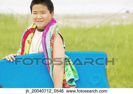 Young boy holding a boogie board smiling View Large Photo Image Stock Photograph - Young boy holding a boogie board smiling. Fotosearch
