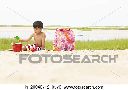 Young boy playing in the sand on the beach View Large Photo Image Stock Photograph - Young boy playing in the sand on the beach. Fotosearch