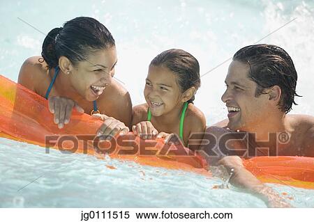 Stock Photography - Young couple and their child resting on an air mattress smiling. Fotosearch