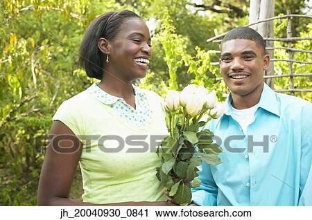 Young couple standing together holding a bunch of flowers View Large Photo Image Stock Image - Young couple standing together holding a bunch of flowers. Fotosearch