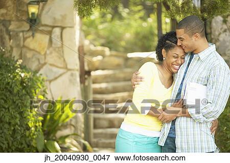 Stock Photo - Young couple standing together holding each other. Fotosearch