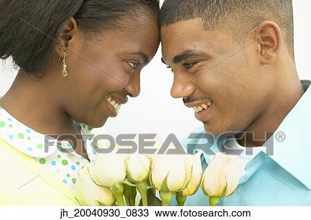 Young couple standing together looking at each other View Large Photo Image Stock Image - Young couple standing together looking at each other. Fotosearch