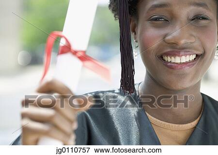 Young female graduate holding a diploma looking at camera smiling View Large Photo Image Stock Photo - Young female graduate holding a diploma looking at camera smiling. Fotosearch