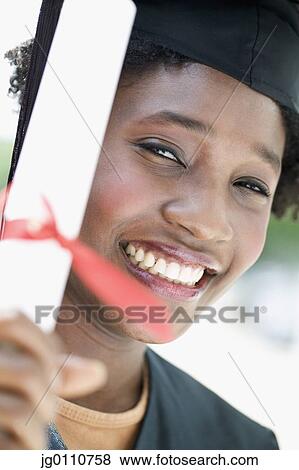 Young female graduate holding a diploma looking at camera smiling View Large Photo Image Stock Photo - Young female graduate holding a diploma looking at camera smiling. Fotosearch