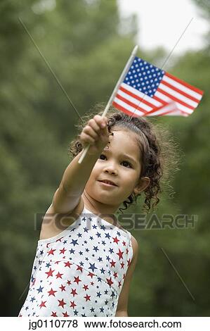Stock Photo - Young girl holding up an American flag. Fotosearch