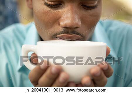 Young man holding a cup of coffee View Large Photo Image Stock Image - Young man holding a cup of coffee. Fotosearch
