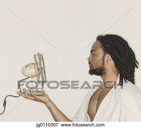 Stock Photo - Young man holding a fan in front of his face. Fotosearch