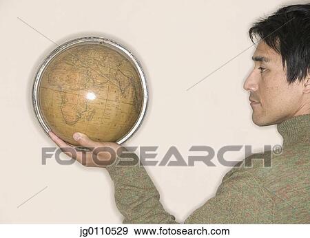 Young man holding a globe View Large Photo Image Stock Photo - Young man holding a globe. Fotosearch