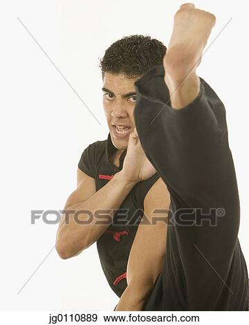 Stock Photo - Young man performing marital arts looking at camera. Fotosearch