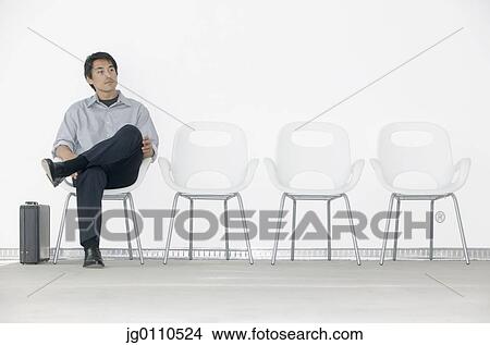 Young man sitting on a chair waiting View Large Photo Image Picture - Young man sitting on a chair waiting. Fotosearch