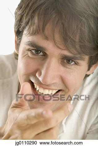 Young man smiling pointing his finger towards camera View Large Photo Image Stock Image - Young man smiling pointing his finger towards camera. Fotosearch