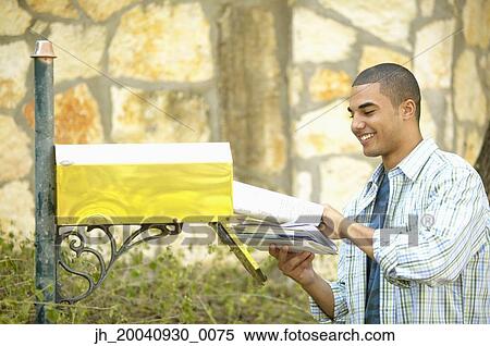 Young man taking out mail from a mail box View Large Photo Image Stock Photography - Young man taking out mail from a mail box. Fotosearch
