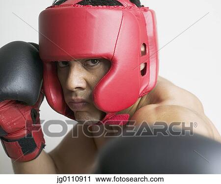 Stock Image - Young man wearing boxing gear looking at camera. Fotosearch