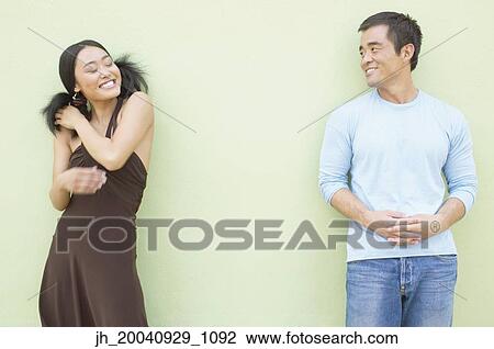 Young woman and a mid adult man standing against a wall smiling View Large Photo Image Stock Image - Young woman and a mid adult man standing against a wall smiling. Fotosearch
