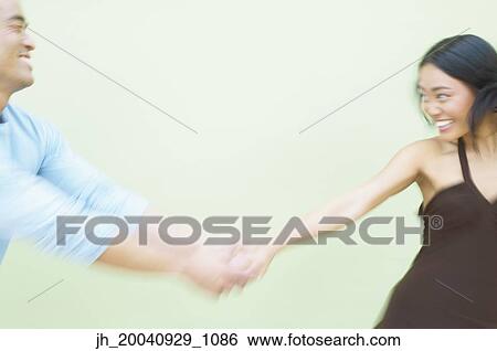 Stock Photograph - Young woman and a mid adult man walking together holding hands. Fotosearch